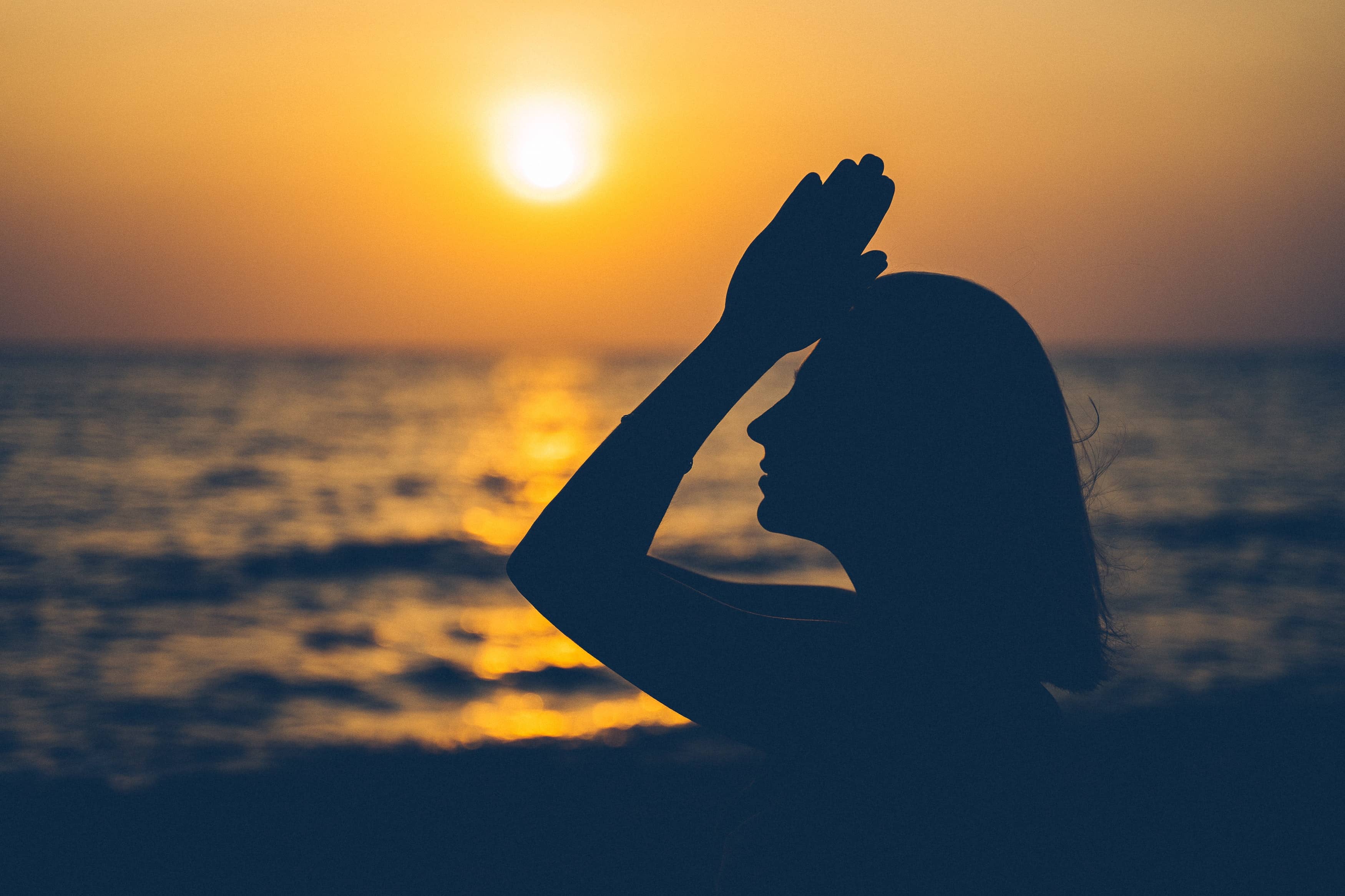 femme faisant du yoga devant un coucher de soleil